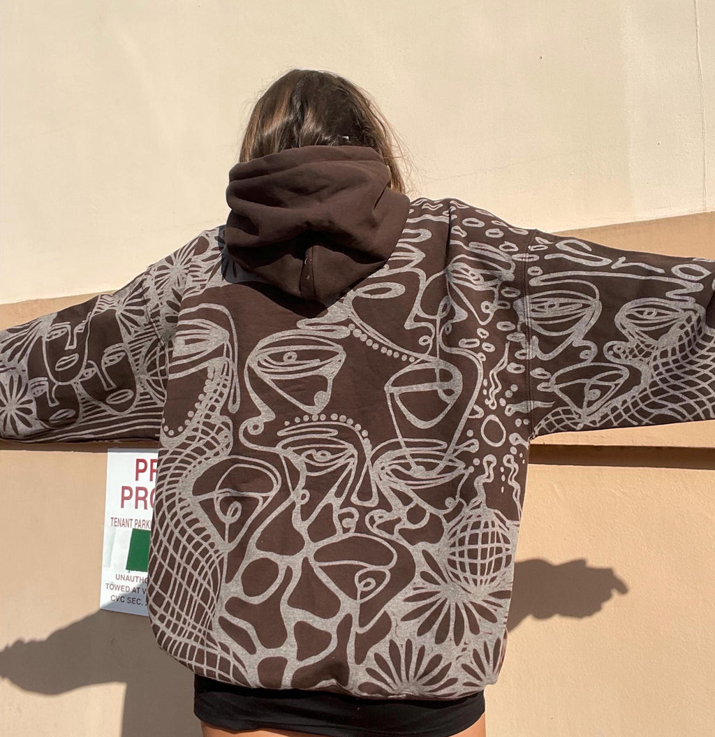 Abstract faces, spiral geometric pattern, and celestial sun print style hoodie in golden tan/yellow and white/ cream
