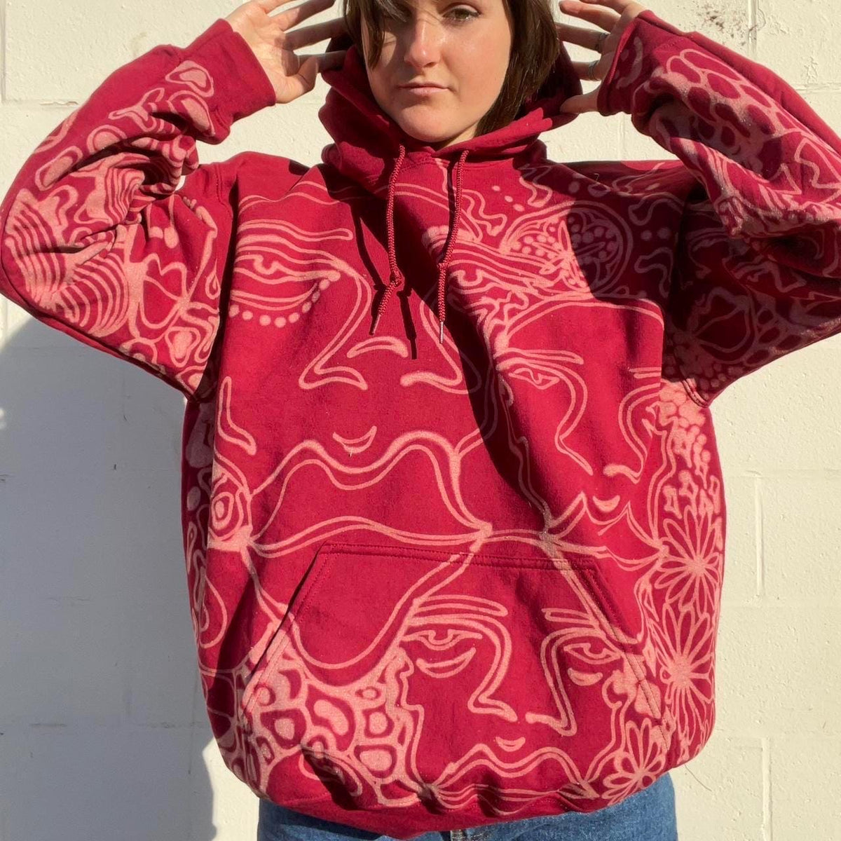 .Abstract faces, floral pattern, and geometric style hoodie in burgandy and cream